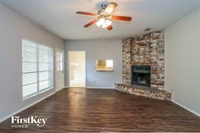 Houston house for rent - an empty living room with a brick fireplace and a ceiling fan