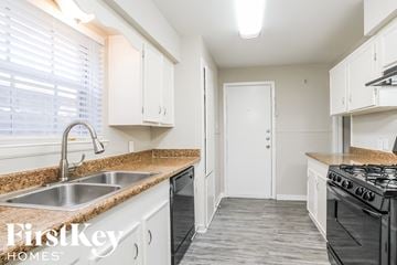 Houston house for rent - a kitchen with white cabinets and granite counter tops and a sink
