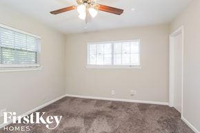 Houston house for rent - a bedroom with carpet and a ceiling fan and two windows