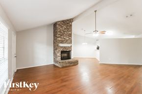 Houston house for rent - A room with a stone fireplace and wooden floors.