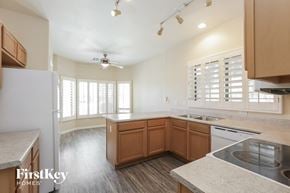 Surprise house for rent - an empty kitchen with wood flooring and white walls and wooden cabinets