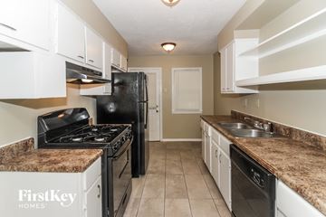 Memphis house for rent - a kitchen with white cabinets and black appliances and granite counter tops