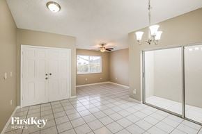 Miami house for rent - A spacious room with a white door, a ceiling fan, and a chandelier.