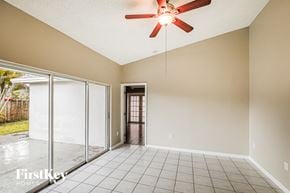 Miami house for rent - A room with a ceiling fan and sliding glass doors.