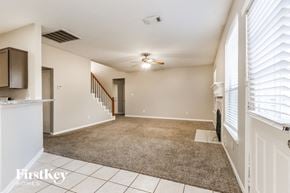 Tomball house for rent - A spacious room with a carpeted floor and a staircase in the background.