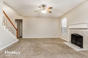 Tomball house for rent - A spacious living room with a fireplace and a ceiling fan.