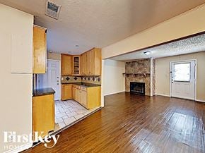 Farmers Branch house for rent - A spacious living room with wood floors and a fireplace.