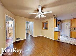 Farmers Branch house for rent - A spacious room with wooden floors and a ceiling fan.