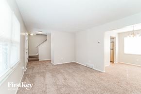 Columbus house for rent - A spacious room with a carpeted floor and a staircase leading to another room.