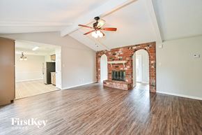 Houston house for rent - A room with a brick fireplace and a ceiling fan.