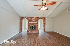 Houston house for rent - A room with a brick fireplace and wood flooring.
