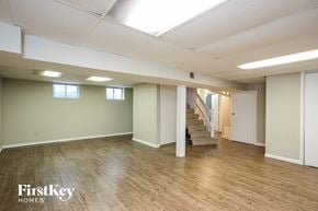 Grandview house for rent - A spacious room with wooden floors and a staircase leading to another room.