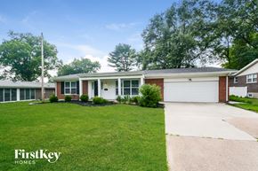 Florissant house for rent - a white and brick house with a lawn and a driveway