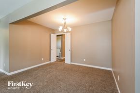 Florissant house for rent - a spacious living room with carpeting and a chandelier