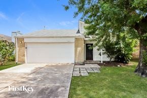 Houston house for rent - A two-car garage with a white door is surrounded by a well-kept lawn and trees.