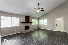 Houston house for rent - A spacious room with a fireplace and a ceiling fan.
