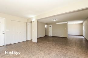Glendale house for rent - A spacious room with tile flooring and white walls, with a door on the left and a window on the right.