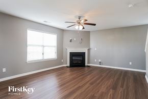 Kernersville house for rent - A spacious room with a fireplace and a ceiling fan.