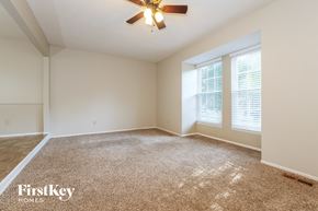 Olathe house for rent - a spacious living room with carpet and a ceiling fan