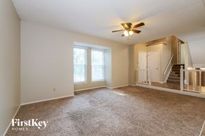 Olathe house for rent - an empty living room with carpet and a ceiling fan