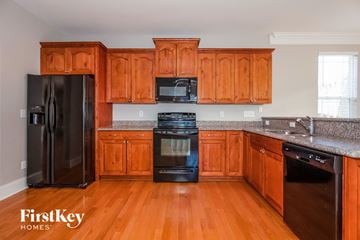 Huntersville house for rent - A kitchen with wooden cabinets and a black fridge.