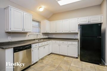 Mansfield house for rent - a kitchen with white cabinets and a black refrigerator