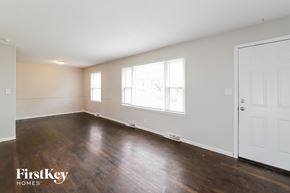 Gladstone house for rent - A room with wooden floors and white walls, with a door on the right side.