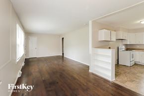 Gladstone house for rent - A spacious room with wooden floors and white walls.