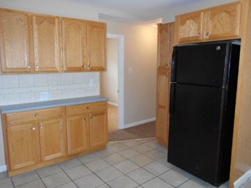 Florissant house for rent - A kitchen with wooden cabinets and a black refrigerator.