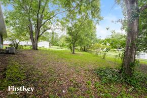Conyers house for rent - A backyard with a gravel area, trees, and a fence.