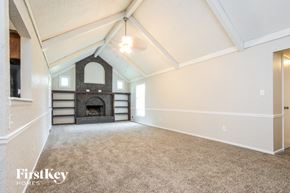 Blue Springs house for rent - A spacious room with a fireplace and a carpeted floor.