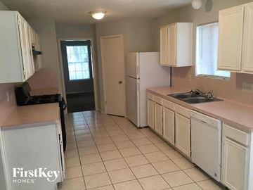 Houston house for rent - a kitchen with white cabinets and a sink and a refrigerator