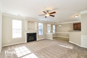 Mcleansville house for rent - A spacious living room with a fireplace and a ceiling fan.