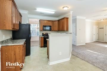 Mcleansville house for rent - A kitchen with wooden cabinets and a black refrigerator.