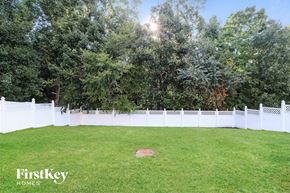 Mcleansville house for rent - A white fence encloses a green lawn with trees in the background.
