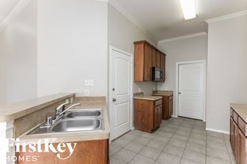 Dallas house for rent - a kitchen with a sink and cabinets and a door to the living room