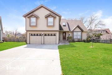 Olathe house for rent - a beige house with a garage and a lawn