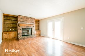 Olathe house for rent - an empty living room with a brick fireplace and wooden floors