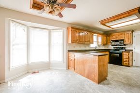 Olathe house for rent - a kitchen with wooden cabinets and a large window
