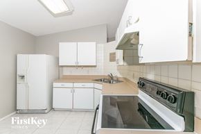 Poinciana house for rent - a kitchen with white cabinets and a stove and a sink