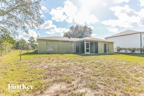 Poinciana house for rent - a small house with a grassy yard and a fence
