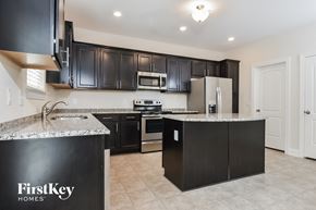 Mcleansville house for rent - a kitchen with black cabinets and granite counter tops