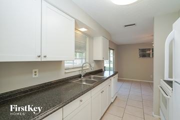 Lehigh Acres house for rent - a kitchen with white cabinets and a granite counter top and a sink