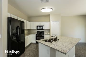 Surprise house for rent - a kitchen with granite counter tops and black appliances