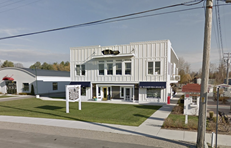 Walloon Lake apartment for rent - A white building with a blue awning sits on a street corner.