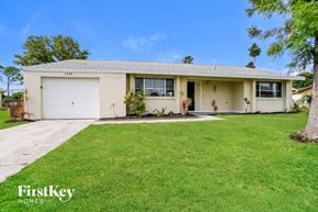 Cape Coral house for rent - A house with a garage and a tree in front of it.