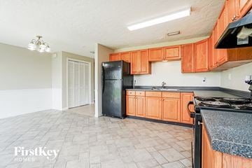 Cape Coral house for rent - A kitchen with orange cabinets and a black fridge.