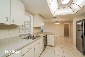 Cape Coral house for rent - A kitchen with white cabinets and a black fridge.