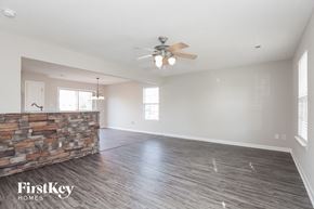 Charlotte house for rent - an empty living room with a ceiling fan and a stone wall