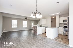 Charlotte house for rent - an open kitchen and living room with white cabinets and a wood floor
